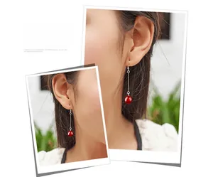 Detail of red agate bead earring hanging on model with elegant silver tassel chain