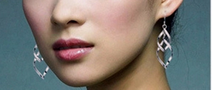 Détail de boucles d'oreilles pendantes en argent portées par un mannequin de profil