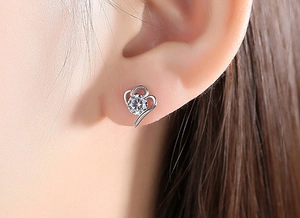 Gros plan d'une boucle d'oreille cœur en argent S925 avec zircon sur l'oreille