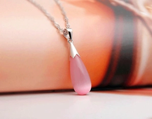 Détail macro du pendentif en pierre oeil de chat rose sur chaîne en argent 925
