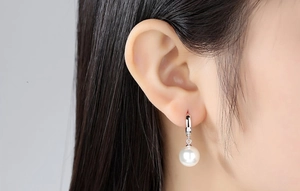 Close-up of S925 sterling silver hoop earring with a round white pearl on a model