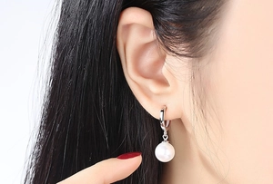 Close-up of S925 sterling silver hoop earrings with round white shell pearls on model