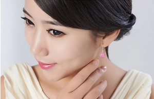 Detail of pink cat-eye stone drop earrings worn by a model showcasing minimalist silver hooks