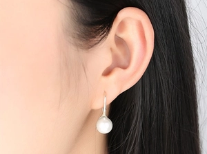 Detail view of 8mm round white pearl earrings worn to show elegant drop style