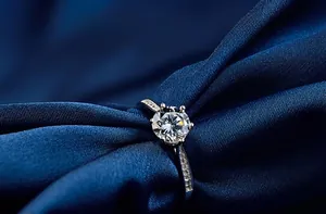 Close-up of s925 silver six-prong engagement ring with round moissanite on silk