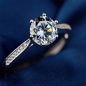 Close-up of classic six-prong s925 silver moissanite ring with side diamonds on blue silk
