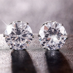 Macro view of brilliant round-cut earrings with six-prong setting in silver finish