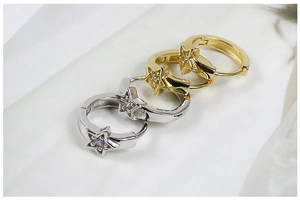 Dettaglio macro di orecchini a cerchio a forma di stella in argento e oro con zircone