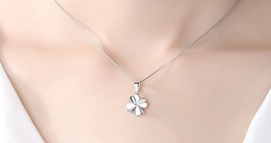 Macro shot of polished S925 sterling silver four-leaf clover pendant on model's neck