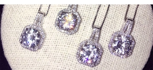 Détail de quatre colliers halo carrés en argent avec pendentifs en zircone sur tissu