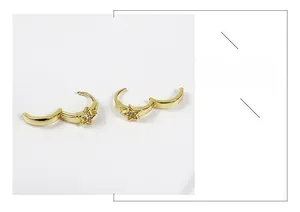 Dettaglio di orecchini a stella dorati con zircone cubico centrale e chiusura a cerchio