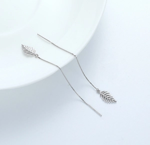 Macro detail of S925 silver leaf earrings with delicate fringe chain on white ceramic