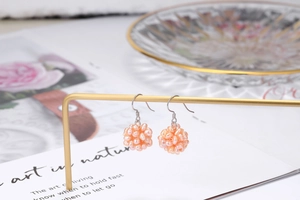 Elegant woven sphere earring detail made of small freshwater pearls on a silver metal hook