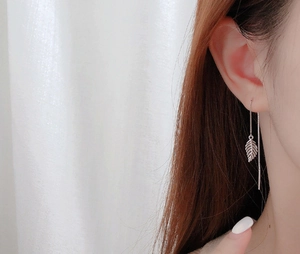 Detail of S925 sterling silver leaf tassel earrings showing delicate texture on model