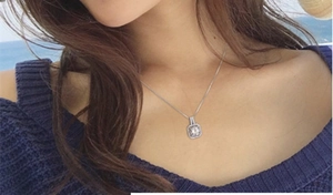 Détail d'un pendentif carré en zircone sur une chaîne en argent porté par un modèle
