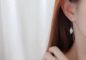 Detail view of S925 silver leaf tassel earrings on model with soft lighting