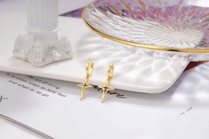 Detail of gold hoop earrings with North Star pendants on a white textured tray