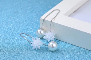 Macro detail of silver long chain earrings with white pearls and star crystal flowers