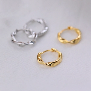 Close-up of twisted Mobius hoop earrings in polished gold and silver metallic finishes