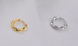 Close-up of Mobius spiral hoop earrings in polished gold and silver finishes