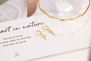 Close-up of gold-plated S925 sterling silver hoop earrings with hollow star charms