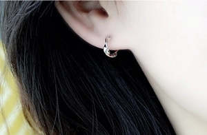 Detail close-up of S925 sterling silver Mobius hoop earring on model's ear