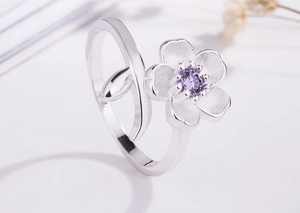 Macro shot of silver cherry blossom ring with matte petals and a purple zircon center