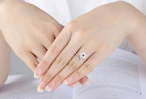 Detail of S925 silver cherry blossom ring with purple gemstone on a book