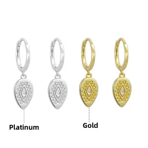 Detailed close-up of water drop earrings in white gold and gold with vintage relief patterns