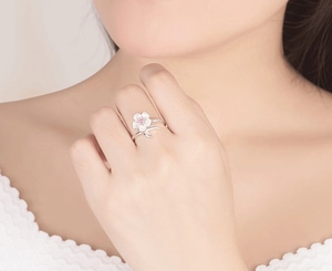 Detail of S925 sterling silver cherry blossom ring with pink cubic zirconia on a finger