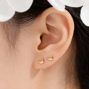 Close-up of elegant gold crescent moon stud earrings worn for a minimalist jewelry look