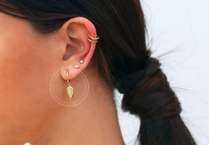 Close-up of gold teardrop earrings with embossed totem and crystal on model