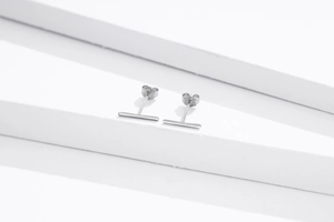 Macro shot of S925 sterling silver bar stud earrings on white geometric props