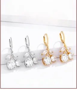 Detailed view of cherry earrings in gold and silver set with sparkling white zircons