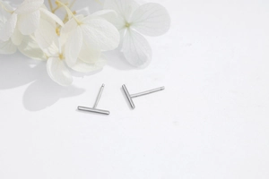 Close-up of minimalist 925 sterling silver T-shaped stud earrings on white surface