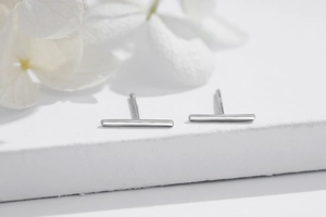 Minimalist 925 sterling silver bar stud earrings with polished finish on stone surface