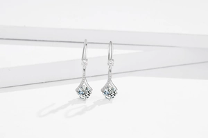 Gros plan sur des boucles d'oreilles pendantes en argent avec zircons blancs et fleurs