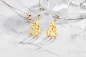 Detailed view of triple-layered gold sterling silver hoop earrings on marble surface