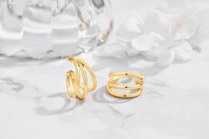 Macro detail of gold-plated geometric triple-layer circle earrings on marble