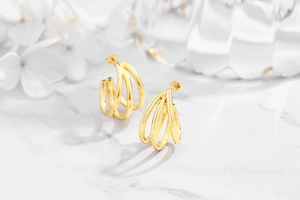 Detailed view of gold triple layered geometric circle stud earrings on white marble background