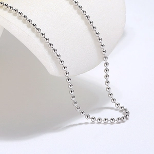 Macro view of polished silver ball chain necklace on a white display pedestal