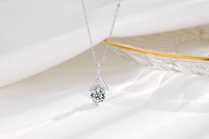 Macro shot of S925 silver necklace with sparkling round zircon on white silk fabric