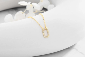 Detail of 925 silver gold-plated necklace with oval pendant set with zircon stones