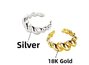 Macro detail of twisted rope ear cuffs in silver and 18K gold finishes on white background