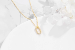 Macro view of gold-plated oval pendant with pave-set cubic zirconia on marble background