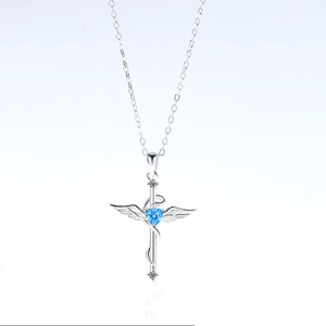 Detalle del collar cruz alas de ángel en plata 925 con gema azul de corazón