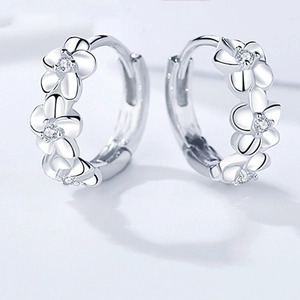 Detail of 925 sterling silver floral huggie hoop earrings with sparkling zircon stones