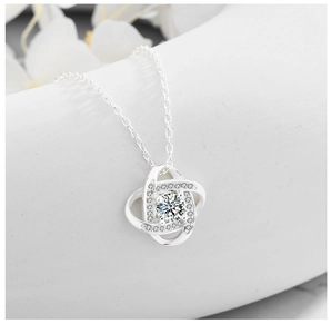 Detailed close-up of a silver clover pendant necklace with sparkling crystal inlay