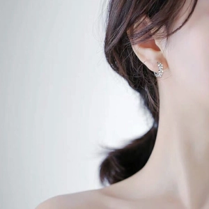 Close-up of 925 sterling silver hoop earrings with delicate floral texture on a model
