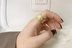 Détail d'une bague dorée texturée de style vintage portée sur la main d'un mannequin